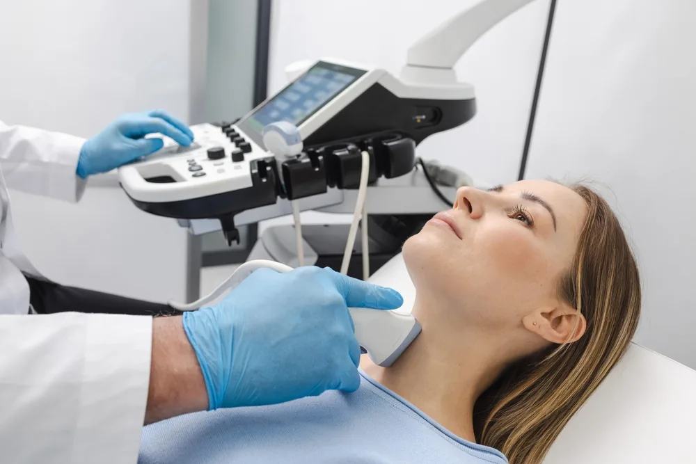 Clinician performing thyroid ultrasound on a patient using handheld ultrasound device